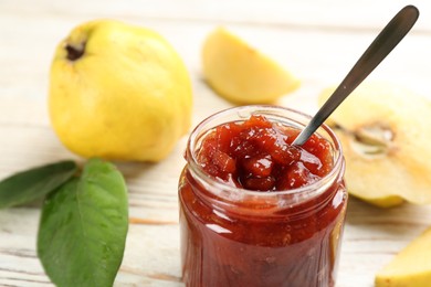 Photo of Delicious quince jam and fruits on white wooden table, closeup