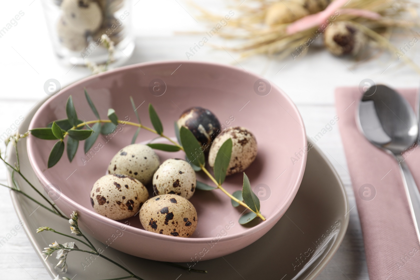 Photo of Festive Easter table setting with quail eggs and floral decor on wooden background, closeup