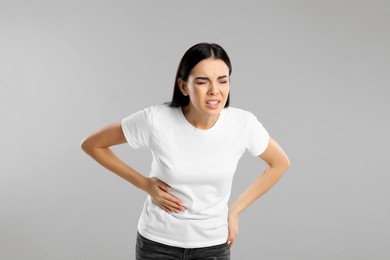 Photo of Woman suffering from liver pain on grey background