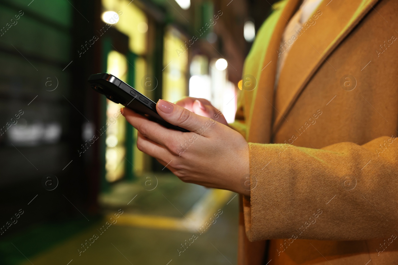 Photo of Woman with smartphone on night city street, closeup