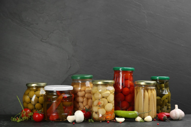 Jars of pickled vegetables on grey background