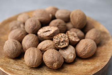 Photo of Wooden board with nutmegs on light grey background, closeup
