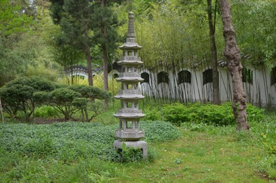 Stone Japanese pagoda sculpture on green grass in park