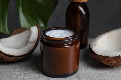 Photo of Jar of hand cream and coconut pieces on grey table