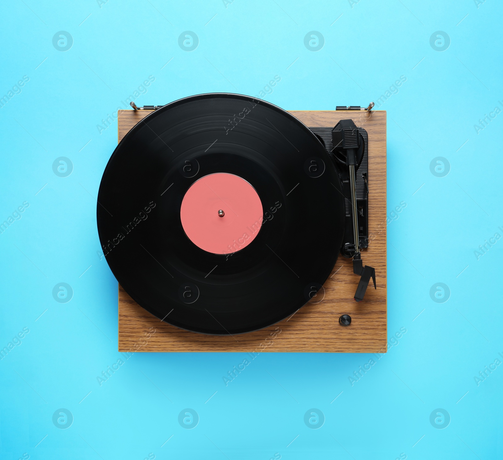 Photo of Modern turntable with vinyl record on light blue background, top view