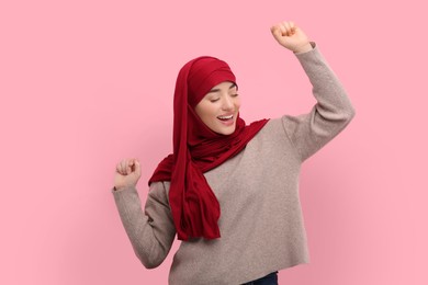 Photo of Muslim woman in hijab dancing on pink background