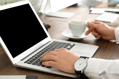 Man using laptop at table, closeup. Space for design