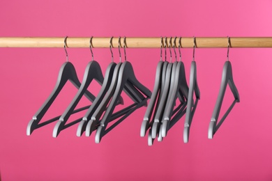 Wooden rack with clothes hangers on color background