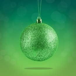 Image of Beautiful glittery Christmas ball hanging on green background