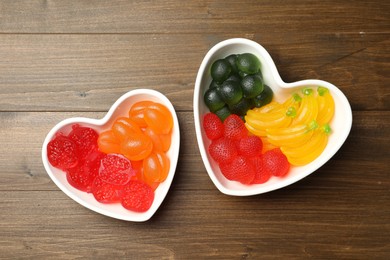 Delicious gummy fruit shaped candies on wooden table, flat lay