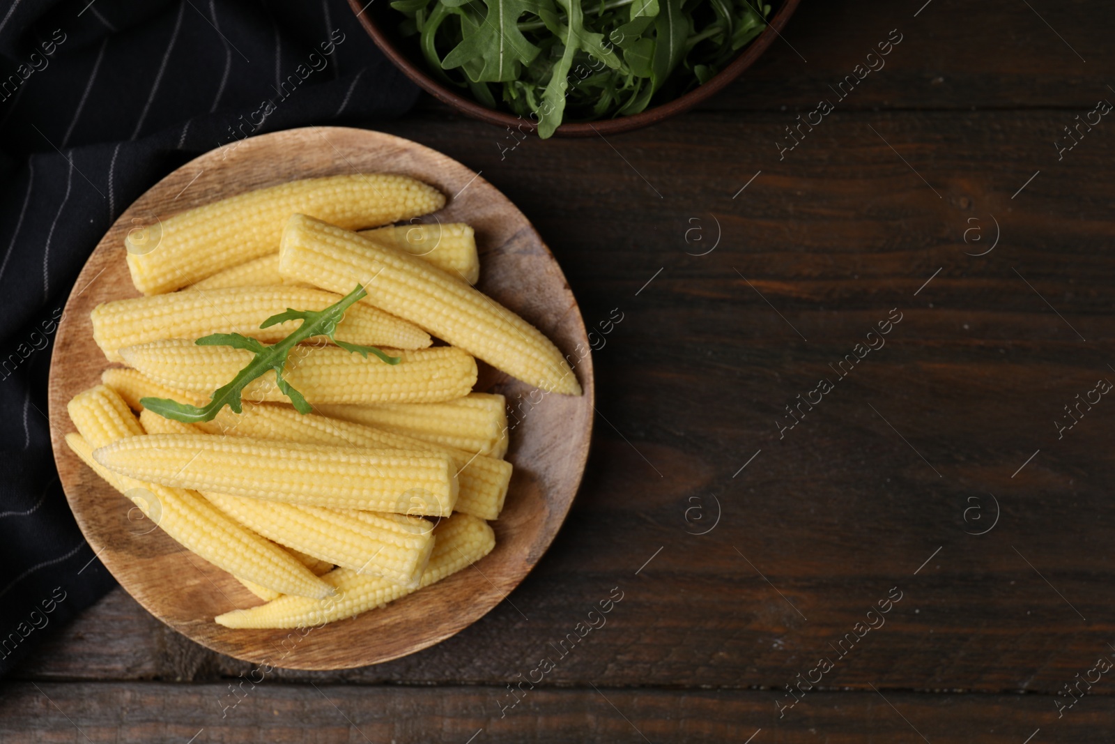 Photo of Tasty fresh yellow baby corns on wooden table, top view. Space for text