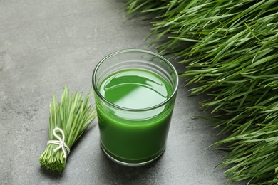 Photo of Composition with glass of wheat grass juice on grey stone background