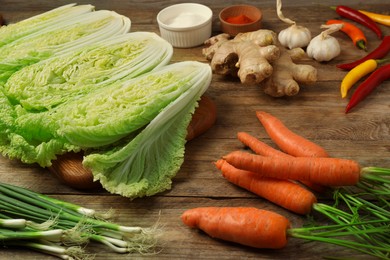 Photo of Cut fresh ripe Chinese cabbages and ingredients on wooden table