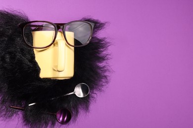 Man's face made of artificial beard, cup and glasses on purple background, top view. Space for text