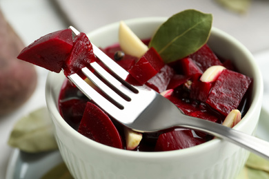 Photo of Pickled beets with garlic in bowl on table, closeup