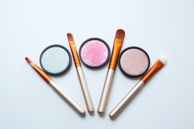 Photo of Makeup brushes with cosmetics on white background