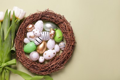 Flat lay composition of painted Easter eggs and tulip flowers on light green background. Space for text