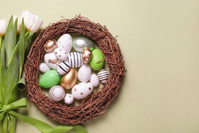 Photo of Flat lay composition of painted Easter eggs and tulip flowers on light green background. Space for text