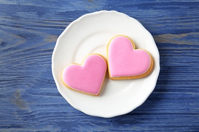 Photo of Plate with decorated heart shaped cookies on wooden background, top view