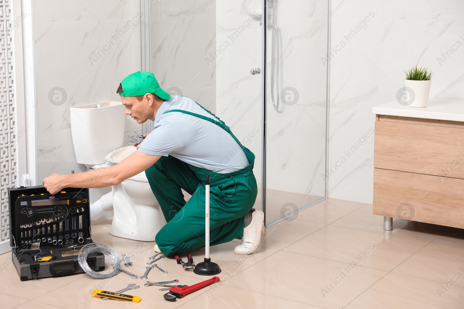 Photo of Professional plumber repairing toilet tank in bathroom