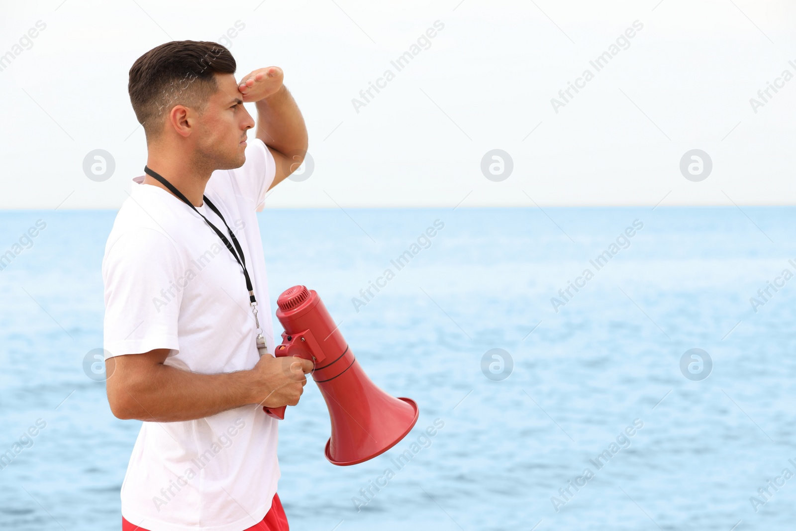 Photo of Handsome male lifeguard with megaphone near sea