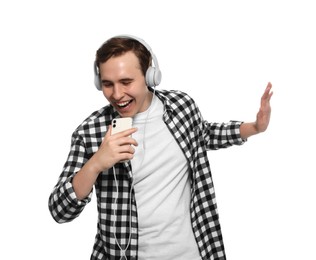 Handsome young man with headphones and smartphone singing on white background