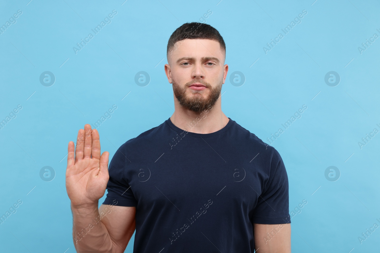 Photo of Man showing stop gesture on light blue background