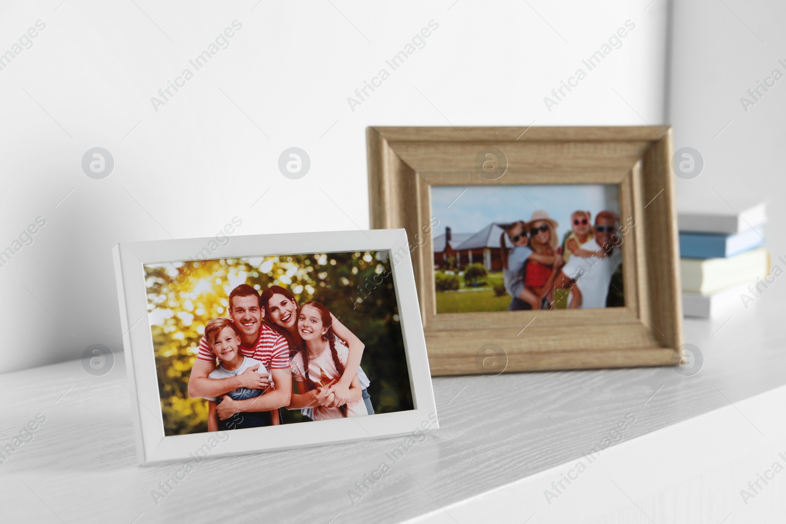 Photo of Frames with family photos on white wooden table indoors