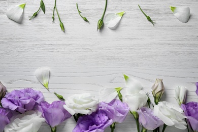 Photo of Flat lay composition with beautiful Eustoma flowers on light wooden background