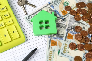 Photo of Calculator, house model, keys and money on documents. Real estate agent's workplace