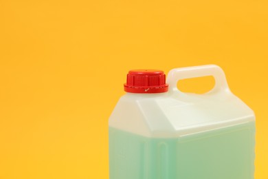 Photo of Plastic canister with green liquid on orange background, closeup. Space for text
