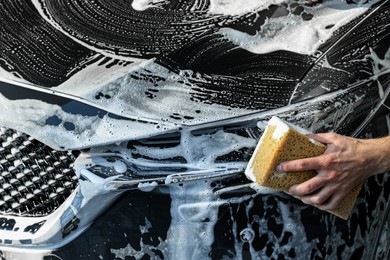 Photo of Worker washing auto with sponge, closeup view
