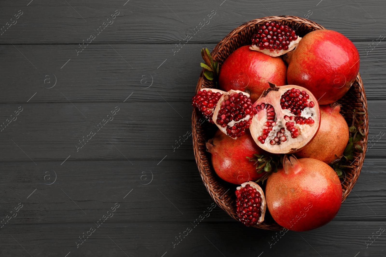 Photo of Delicious ripe pomegranates on grey wooden table, top view. Space for text