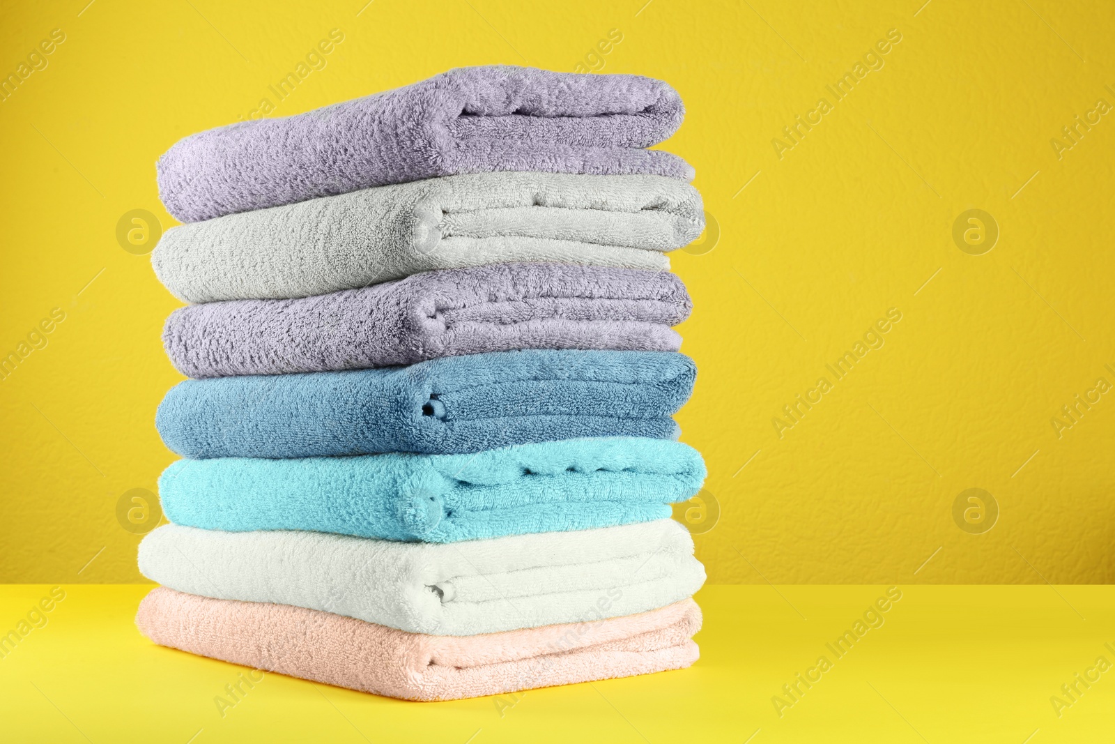 Photo of Different fresh soft terry towels on yellow background