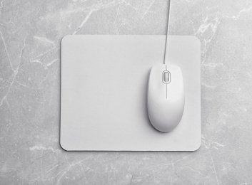 Photo of Wired computer mouse and pad on light grey marble background, flat lay. Space for text