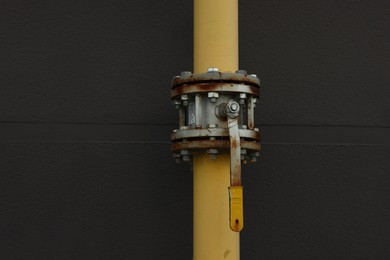 Yellow gas pipe with valve near brick wall outdoors