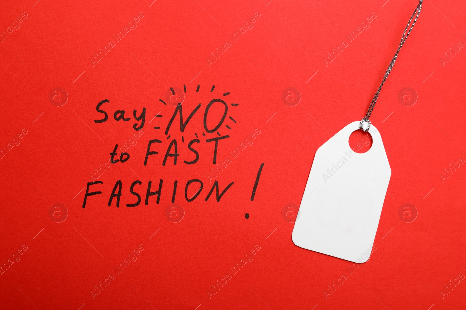 Photo of Tag and phrase SAY NO TO FAST FASHION! written on red background, top view