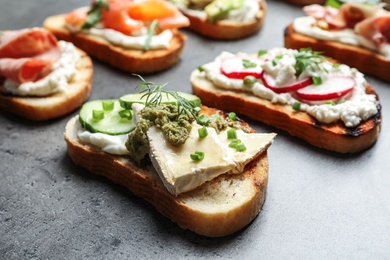 Photo of Many different tasty bruschettas on grey table