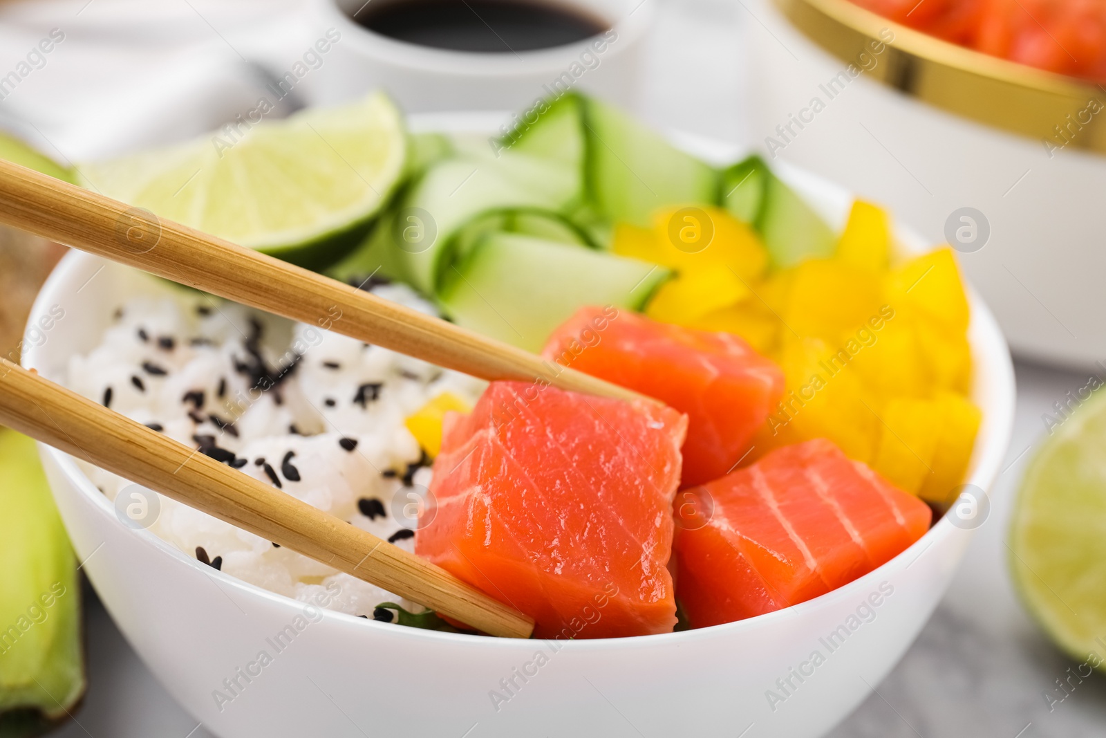 Photo of Delicious poke bowl with salmon, lime and vegetables on table, closeup