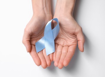 Photo of International Psoriasis Day. Woman with light blue ribbon as symbol of support on white background, top view
