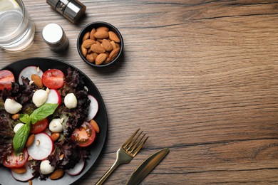 Photo of Delicious vegetable salad with mozzarella served on wooden table, flat lay. Space for text