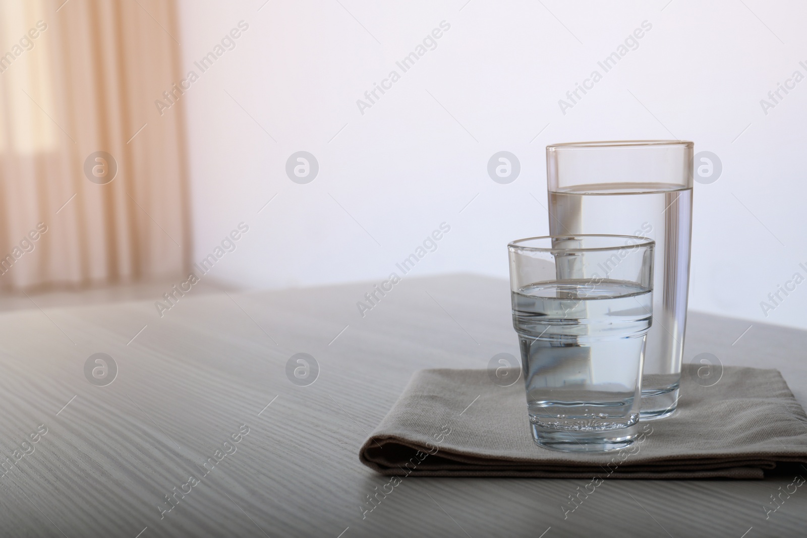 Photo of Glasses of water on table against blurred background. Space for text