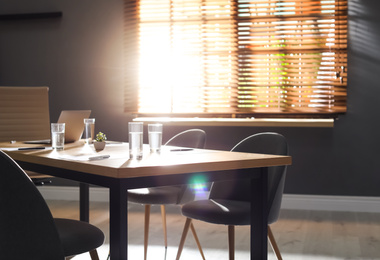 Stylish office interior with wooden table in morning