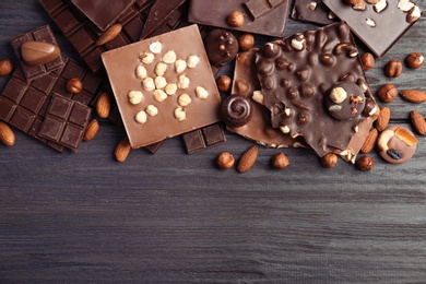 Photo of Different delicious chocolate bars and candies on wooden table, top view
