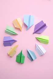 Frame of many colorful paper planes on pink background, flat lay with space for text. Diversity concept