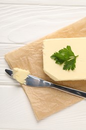 Tasty butter and knife on white wooden table, top view