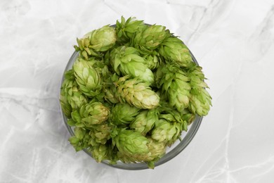 Photo of Bowl of fresh green hops on light grey marble table, top view
