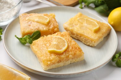 Photo of Tasty lemon bars and mint on table, closeup