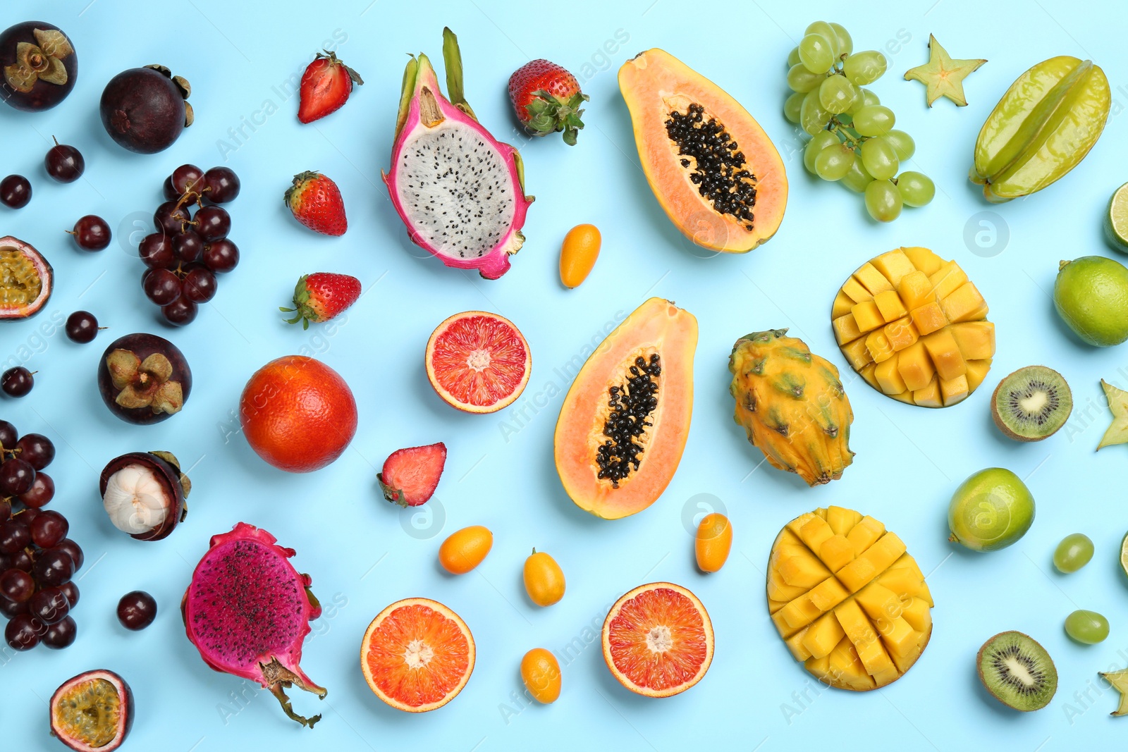 Photo of Many different delicious exotic fruits on light blue background, flat lay
