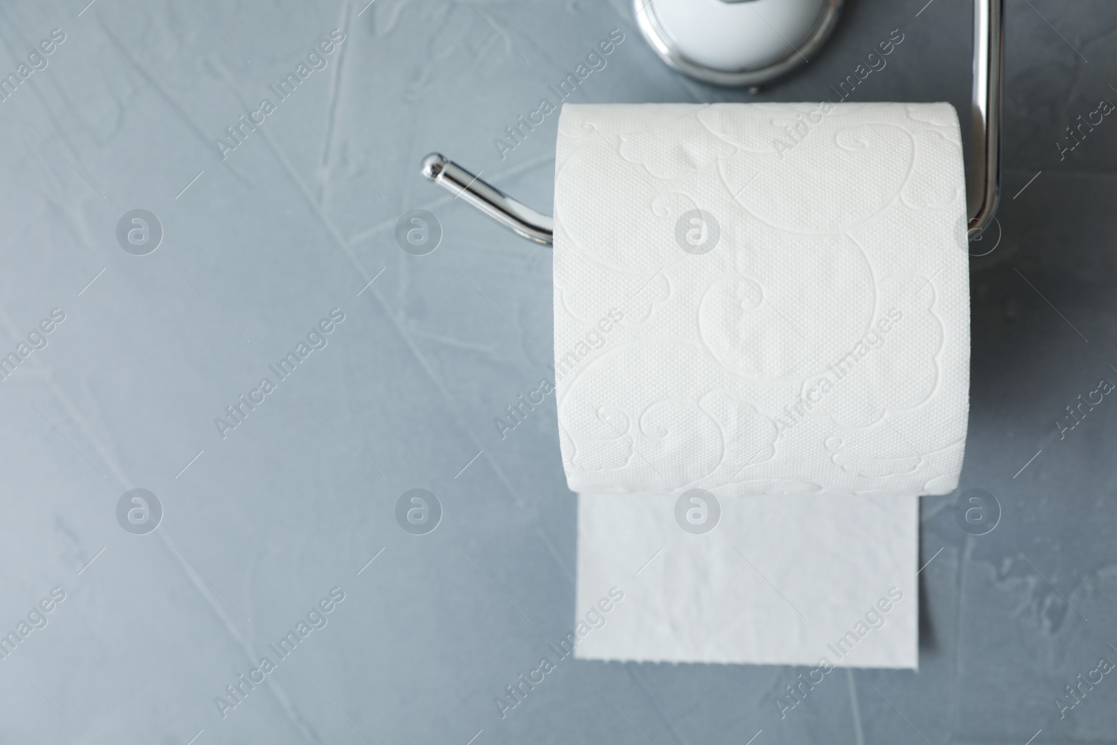 Photo of Holder with toilet paper roll on gray background. Space for text